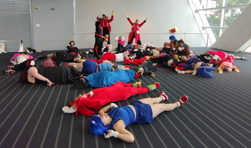 Group photo for the Sonic fandom: the good guys in defeated poses along the convention carpet, while the three Eggman cosplayers stand over them triumphant.