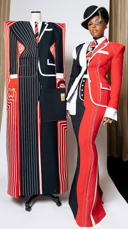 Janelle wearing the second layer of their gala outfit, with the outer boxy overcoat on display next to them.