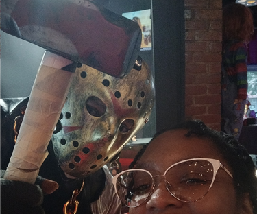 An actor dressed as Jason, with iconic hockey mask. I'm smiling as I pose with him holding his fake weapon over my head.