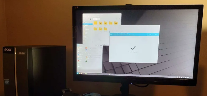 A wide computer monitor, with the Acer Aspire tower next to it. The computer is on and showing the Linux Mint desktop.
