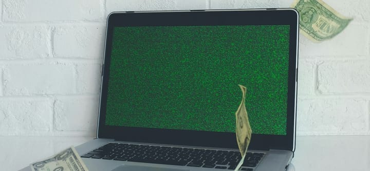 A laptop with dollar bills floating around it. The screen, also, is just green gibberish.